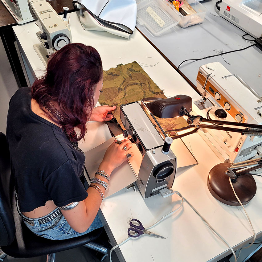 Vue de dessus d'une femme en train de coudre dans l'atelier vêtementssecondemainGenève secondevievêtementsGenève économiecirculaireGenève achatsolidaireGenève boutiquesecondemainGenève friperieGenève donnervêtementsGenève donsolidaireGenève atelierdecoutureGenève RenfileGenève
