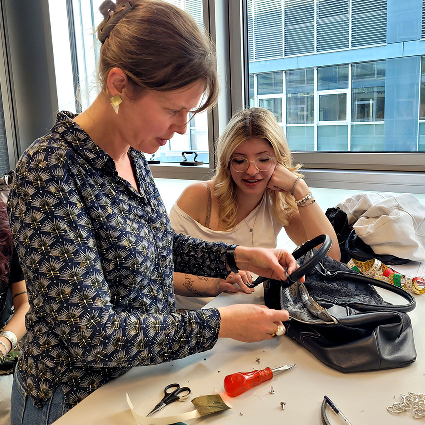 Deux femmes réparant soigneusement un sac en cuir vêtementssecondemainGenève secondevievêtementsGenève économiecirculaireGenève achatsolidaireGenève boutiquesecondemainGenève friperieGenève donnerobjetsGenève donsolidaireGenève maroquineried’occasion RenfileGenève